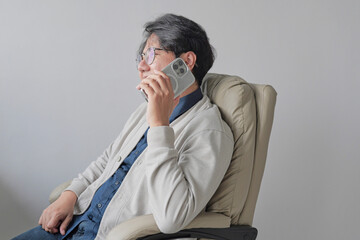 A man is sitting in a chair and talking on his cell phone