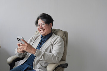 A man is sitting in a chair and holding a cell phone
