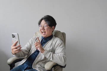 A man is sitting in a chair and holding a cell phone