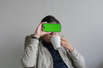 A man is holding a green phone in front of his face