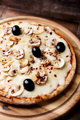 Pizza with champignons, black olives and mozzarella cheese. Wooden background. Soft focus.	