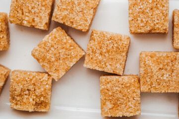Brown sugar cubes scattered on a white surface with a clean background
