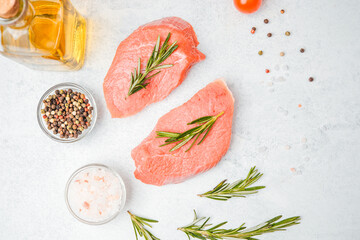 Top view of veal steaks with spices and herbs on white background including close-up of oil and...