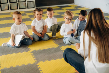 Thinking, learning, sitting on the table. Children in kindergarten with their teacher