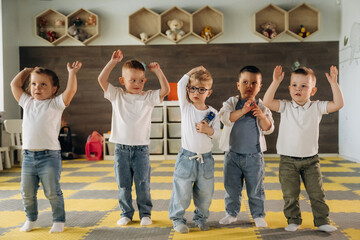 Hands up, standing having fun. Group of children are in the kindergarten