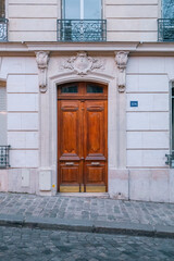 A classic brown wooden front door set in an elegant, carved stone facade in Paris, France.