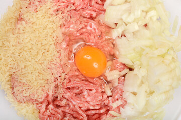 Overhead shot captures ingredients for stuffed peppers, including raw ground meat, uncooked rice,...