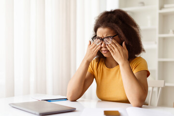 Exhausted black woman rubbing tired eyes, suffering from eyestrain after using laptop, african...