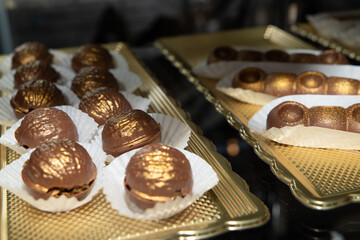 Luxurious handmade decorative chocolates in a display case of assorted pralines with selective accent.