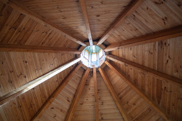 The wooden ceiling of a building has a circular hole in the middle