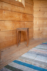 A wooden stool sits in front of a wooden wall
