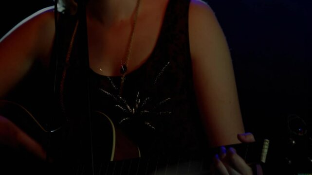 Musician strumming guitar on stage causing spark light while camera rising revealing singing at mic