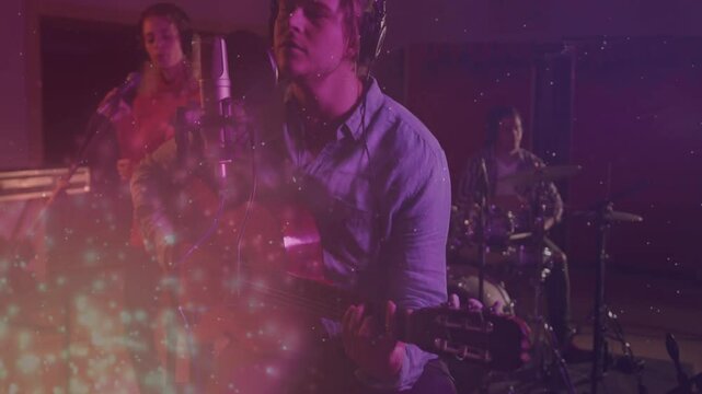 Guitarist leaning into mic, singing in studio with sparkle overlay, bandmates harmonizing drumming