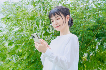 スマートフォンを操作する屋外での爽やかな30代女性