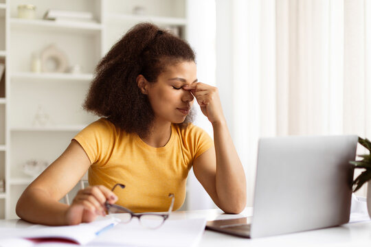 Tired Young Black Woman Feeling Eyes Strain After Using Laptop At Home, African American Female Freelancer Sitting At Desk With Computer At Home Office And Rubbing Nosebridge, Copy Space