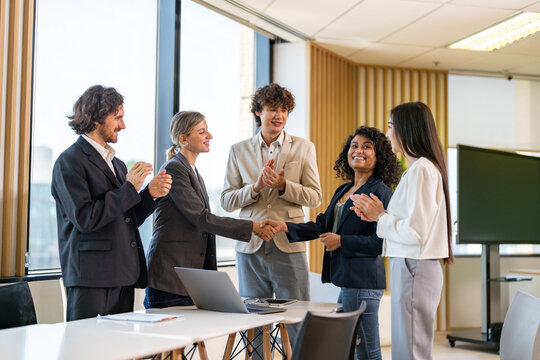 Image two business partners in elegant suit successful handshake together in front of group of casual business clapping hands in modern office.Partnership approval and thanks gesture concept