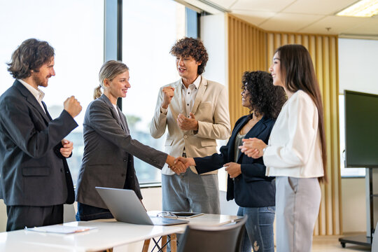Image two business partners in elegant suit successful handshake together in front of group of casual business clapping hands in modern office.Partnership approval and thanks gesture concept