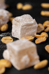 Turkish delight with peanuts, scattered sweets Turkish delight with peanuts on a black board