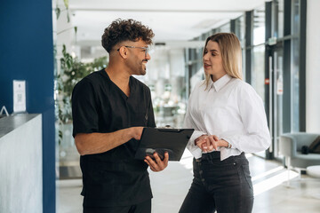 Showing information in notepad. Man and woman are indoors in modern building