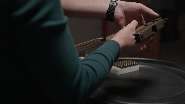 Cropped shot of unrecognizable female trainee getting guidance from instructor while reloading handgun at indoor range