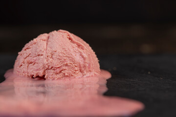 melting pink ice cream on a black board, sweet cold pink ice cream with strawberry flavor