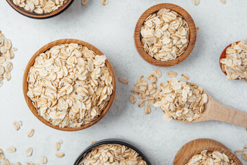 Oats in wooden bowls arranged on a light surface with scattered grains