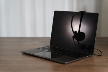 All center and customer service sleek laptop with black headset resting its screen, placed wooden table minimalistic setting, creating