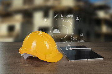 Engineer architect industry 4.0 image shows yellow safety helmet placed wooden table next to tablet with digital icons and graphics floating above