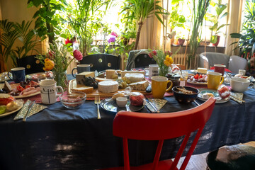 Large dining table, fully set with cheese, sausage and more delicacies for a meal with family or friends in a living room, selected focus