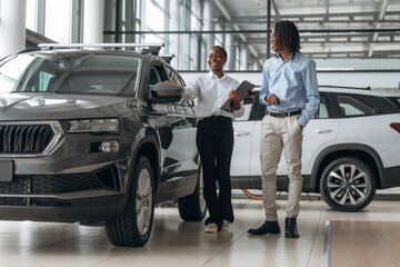 Showing the vehicle. Car seller is assisting client in the automobile salon