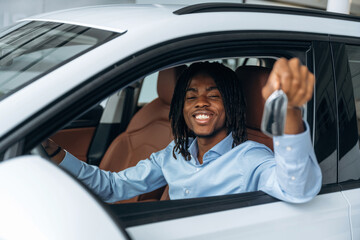 Window is opened, showing keys. Man in shirt is in the modern car