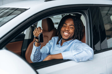 Toothy smile, happy. Man in shirt is in the modern car