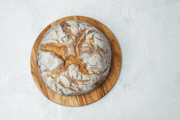 Freshly baked round bread on a wooden board in a bright kitchen
