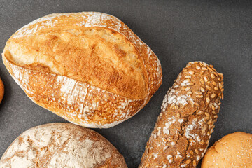 Various types of freshly baked bread displayed on a dark surface
