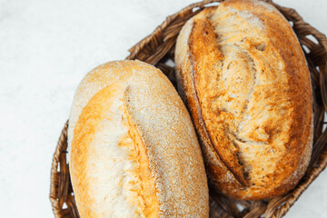 Freshly baked artisan bread in a woven basket on a white background