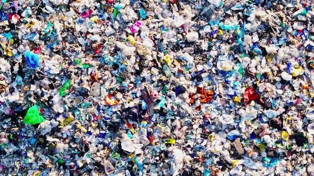 Plastic pollution revealed in top down, drone descends toward toy in waste, 4K