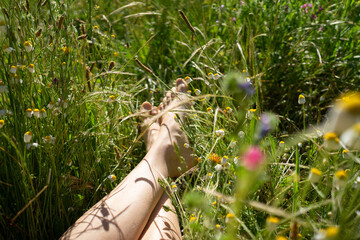 Woman relaxing with bare feet in wildflower meadow