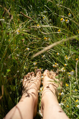 Barefoot relaxing in green grass and chamomile flowers