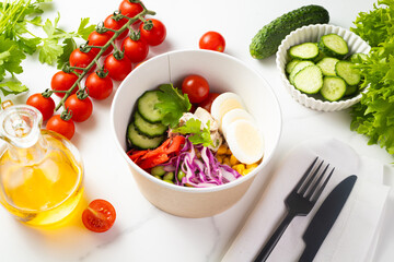 Fresh vegetable salad with egg, cherry tomatoes, cucumbers, mix lettuce leaves and red cabbage . Healthy take away food in cardboard box. Side view
