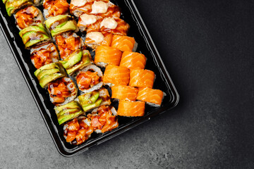 Sushi platter featuring assorted rolls and fresh salmon on a black background