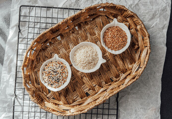 Different types of  seeds displayed in bowls on a woven tray