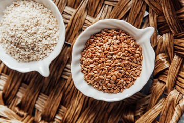 Different types of  seeds displayed in bowls on a woven tray
