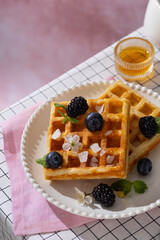 Belgian whole wheat waffles with blueberry on a white table rose background. Breakfast time. Vertical
