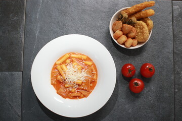 Korean Rose Tteokbokki, a creamy spicy rice cake dish topped with cheese, served with assorted...