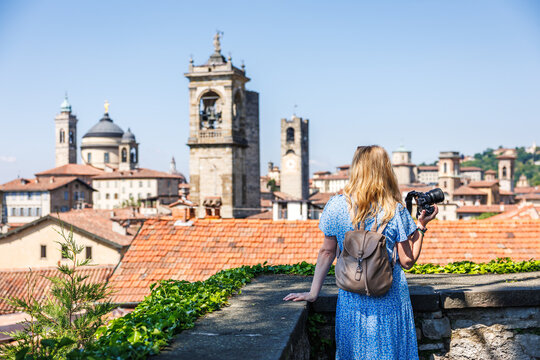 Woman tourist photographing on camera city skyline in Citta Alta, Bergamo, Italy during city break vacation. Summer holiday in Europe