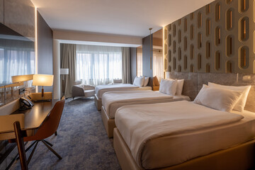 Interior of a triple hotel room photographed in the morning with sunlight
