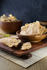 Close-up of traditional crispy tempeh chips which made from fermented soybeans served on a wooden bowl with a rustic setting.Suitable for culinary content, food packaging, advertising, or health food