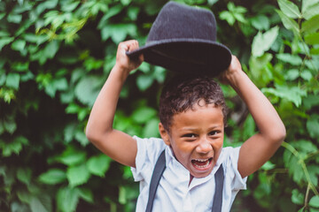 a boy dressed in the style of the 20s shouts raising his hat high, holding the brim with both hands