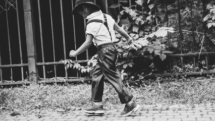 A boy dressed in the style of the 20s jumps down the street side view
