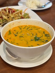 Creamy and spicy Thai red curry (Gaeng Phet or Panaeng) with meat and fresh green vegetables, a vibrant and aromatic coconut milk-based soup, a quintessential dish in Thai cuisine.